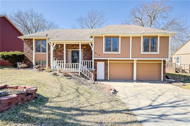 bi-level home with a garage, brick siding, covered porch, and driveway