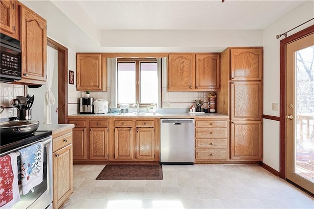 kitchen with light countertops, decorative backsplash, stainless steel appliances, a textured ceiling, and a sink