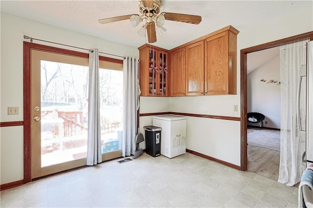 interior space with glass insert cabinets, light floors, brown cabinetry, refrigerator, and a textured ceiling