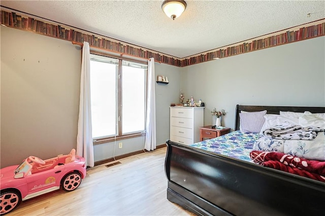 bedroom featuring visible vents, baseboards, a textured ceiling, and light wood-style flooring