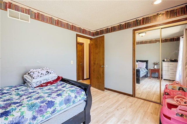 bedroom featuring a textured ceiling, visible vents, a closet, and light wood-type flooring