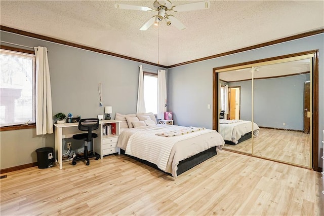 bedroom featuring multiple windows, a textured ceiling, light wood-type flooring, and crown molding