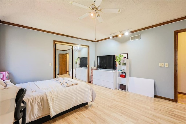 bedroom featuring ornamental molding, light wood-type flooring, visible vents, and a textured ceiling