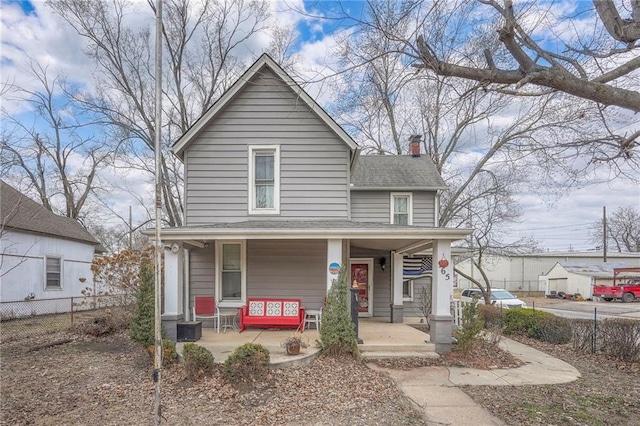 view of front of house featuring covered porch, roof with shingles, fence, and a chimney