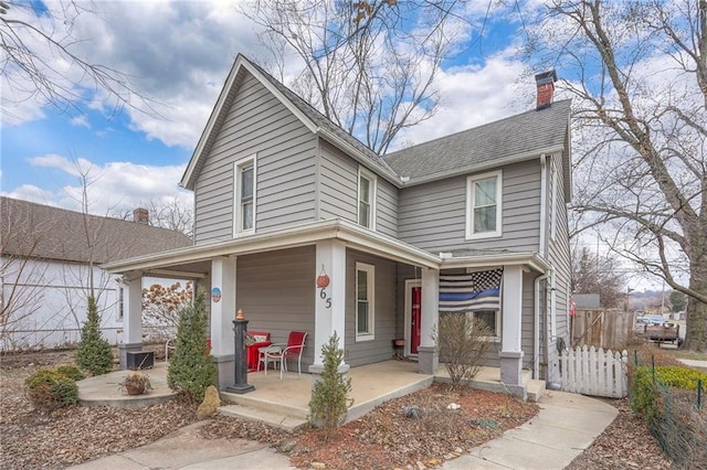 view of front of property featuring a porch, fence, a chimney, and a shingled roof