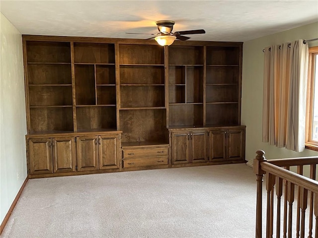 unfurnished living room with light carpet, a ceiling fan, and baseboards