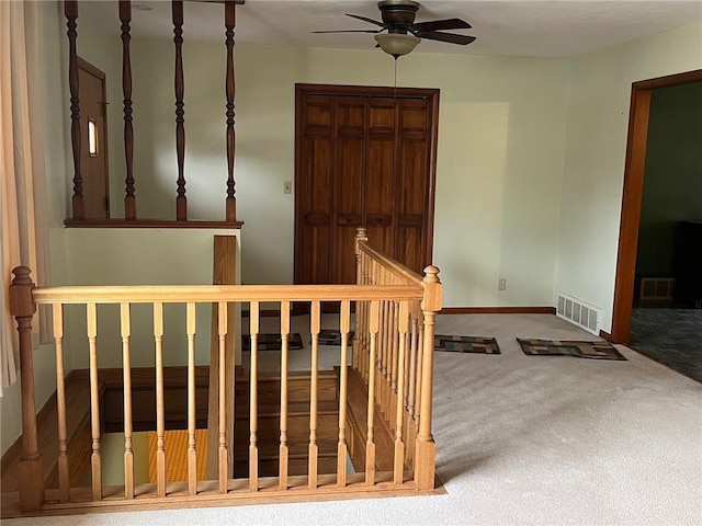 corridor with carpet, baseboards, visible vents, and an upstairs landing