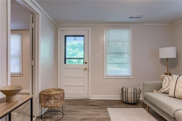 doorway with ornamental molding, wood finished floors, visible vents, and baseboards