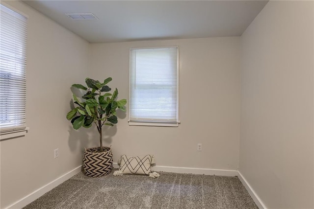 empty room with carpet floors, visible vents, and baseboards