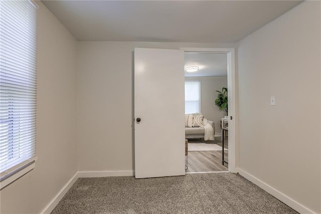 unfurnished bedroom with carpet floors, multiple windows, and baseboards