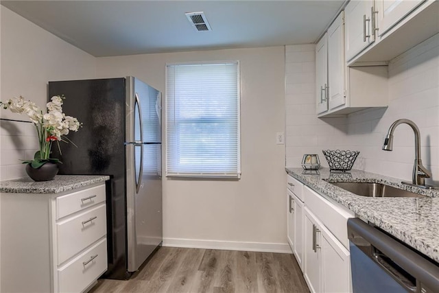 kitchen with visible vents, decorative backsplash, freestanding refrigerator, a sink, and dishwashing machine