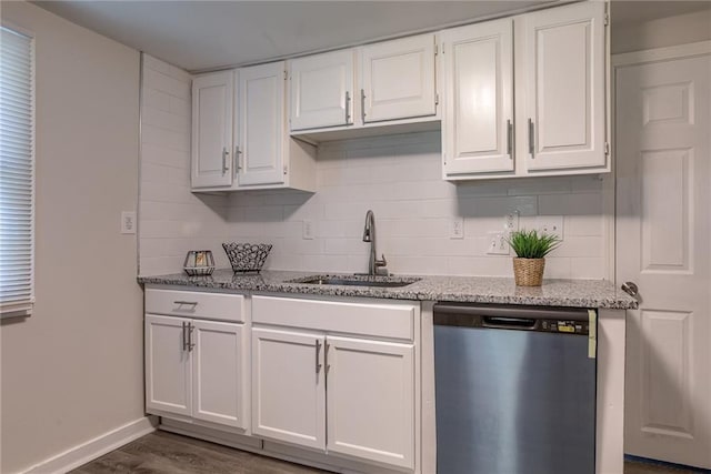 kitchen with light stone counters, tasteful backsplash, white cabinetry, a sink, and dishwasher