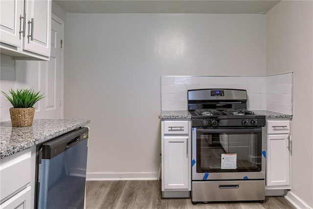 kitchen featuring dishwashing machine, light wood finished floors, stainless steel gas range, and decorative backsplash