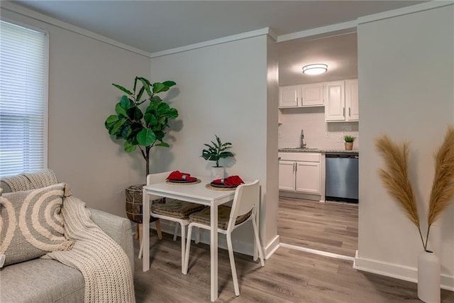 dining room with light wood-style flooring, ornamental molding, and baseboards