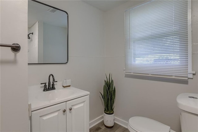 bathroom with toilet, baseboards, wood finished floors, and vanity