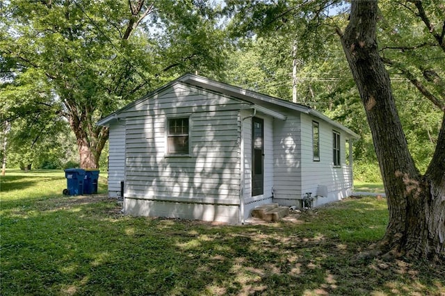 view of property exterior with entry steps and a lawn