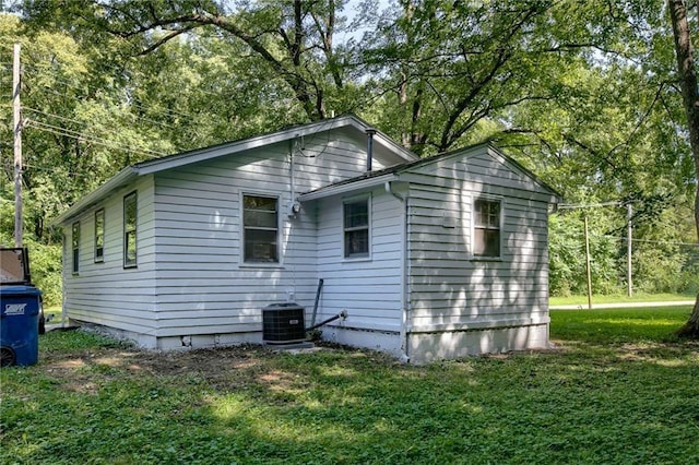 view of side of property featuring central AC and a lawn