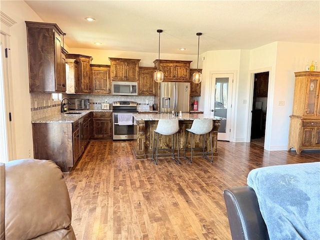 kitchen with dark wood finished floors, tasteful backsplash, appliances with stainless steel finishes, and a sink