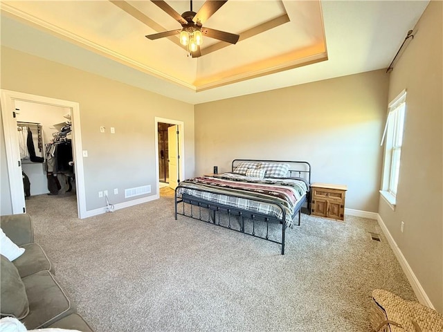 bedroom featuring visible vents, light carpet, baseboards, a raised ceiling, and a spacious closet