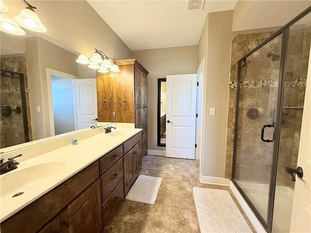 full bathroom with double vanity, a stall shower, baseboards, and a sink