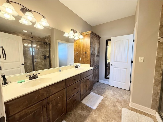 bathroom with double vanity, a stall shower, baseboards, and a sink