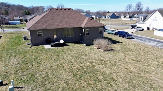 back of property featuring a residential view, central air condition unit, and a yard