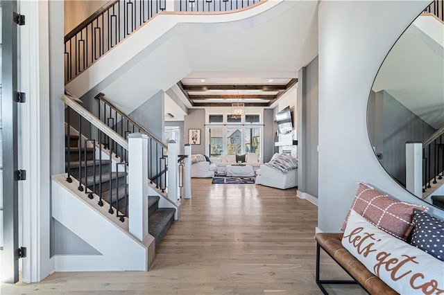 entryway featuring stairs, beamed ceiling, wood finished floors, and baseboards