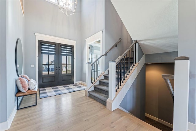 foyer featuring a notable chandelier, wood finished floors, french doors, stairway, and baseboards