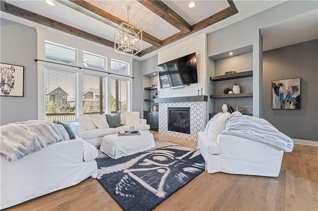 living area featuring beamed ceiling, a notable chandelier, wood finished floors, and built in shelves