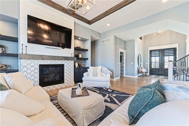 living room featuring visible vents, baseboards, a notable chandelier, and wood finished floors