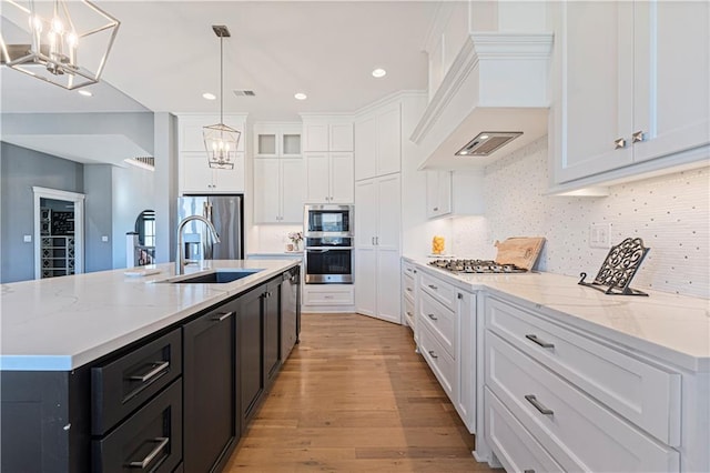 kitchen with a chandelier, dark cabinetry, custom exhaust hood, white cabinetry, and a sink