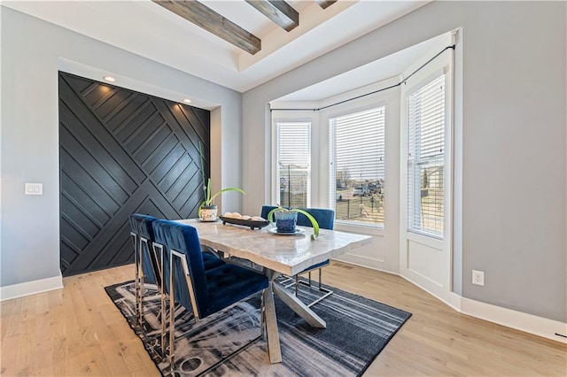 office area with an accent wall, beamed ceiling, baseboards, and light wood-type flooring