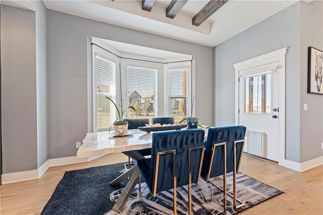 dining space featuring beamed ceiling, light wood-type flooring, and baseboards