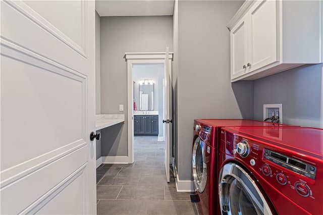 clothes washing area featuring baseboards, cabinet space, separate washer and dryer, and dark tile patterned floors