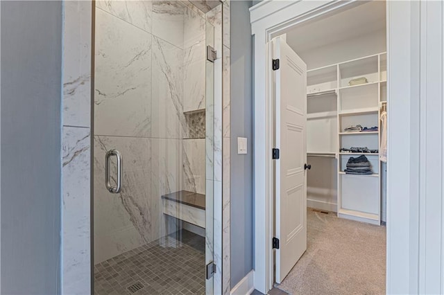 bathroom with a marble finish shower and a walk in closet