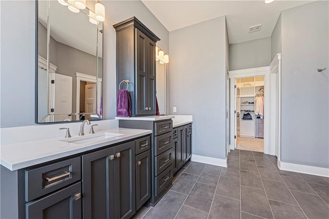 full bath featuring tile patterned flooring, visible vents, a walk in closet, baseboards, and vanity