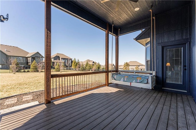 wooden terrace featuring a residential view, a lawn, and a ceiling fan