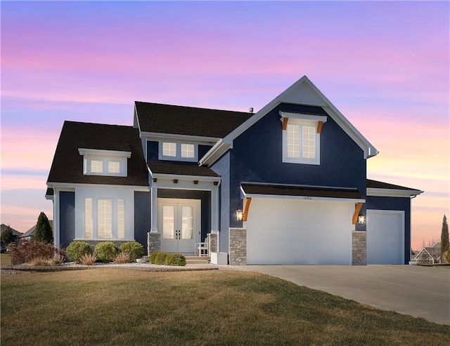 view of front facade with a lawn, french doors, a garage, stone siding, and driveway