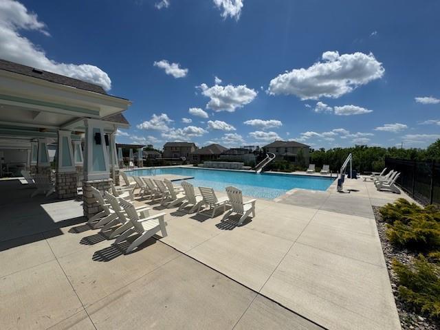 community pool featuring a water slide and a patio