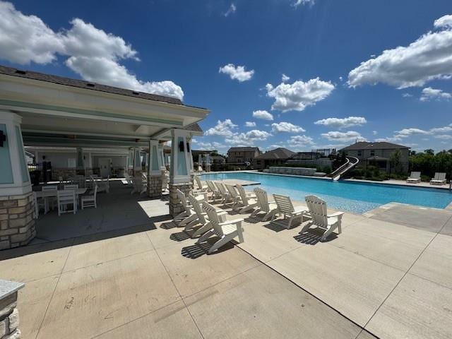community pool with a water slide and a patio area