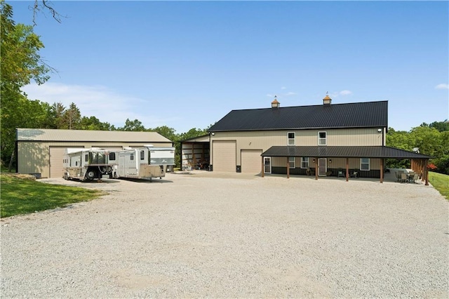 rear view of property with a detached garage and metal roof