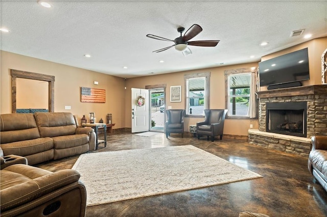 living area featuring a textured ceiling, a stone fireplace, visible vents, and finished concrete floors