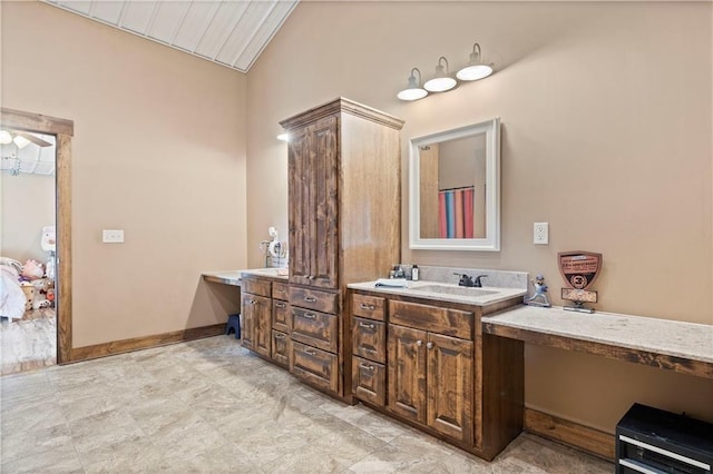 bathroom with vaulted ceiling, vanity, and baseboards