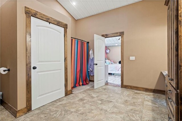 hall with vaulted ceiling and baseboards