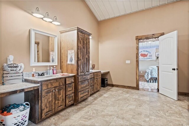 bathroom with lofted ceiling, vanity, and baseboards