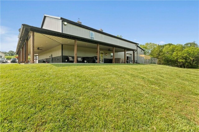 rear view of house featuring a ceiling fan and a yard