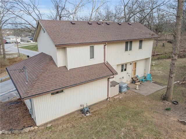756 NW S Shore Dr, Lake Waukomis, MO 64151 - back of property with a shingled roof, a patio area, and a lawn
