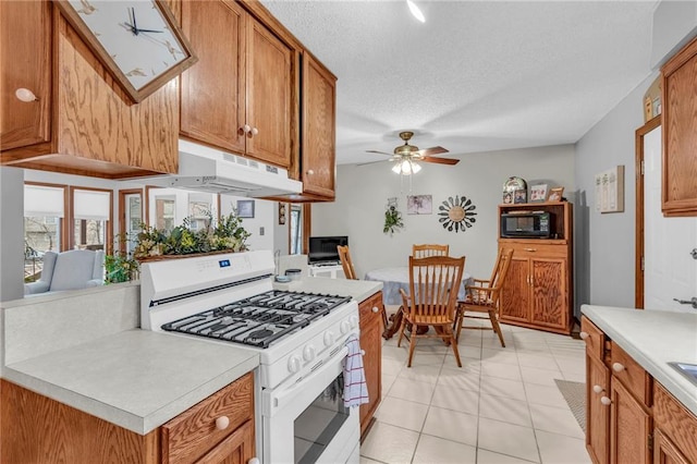 756 NW S Shore Dr, Lake Waukomis, MO 64151 - kitchen with white gas range, black microwave, light countertops, brown cabinets, and a ceiling fan