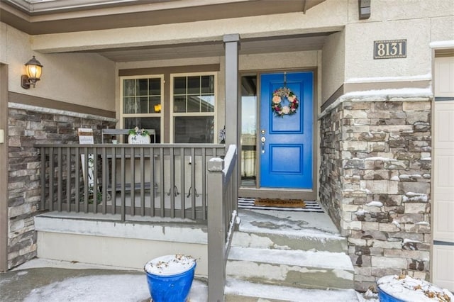 property entrance featuring stone siding, a porch, and stucco siding