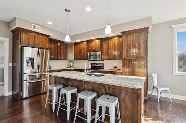 kitchen with visible vents, backsplash, light stone counters, appliances with stainless steel finishes, and a sink